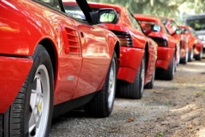 A row of sleek red Ferraris parked neatly along the roadside, showcasing their vibrant color and design.